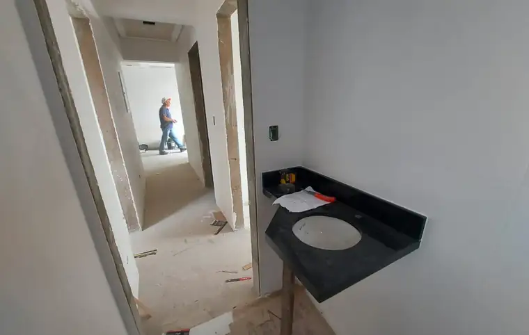 Bancada de banheiro instalada, com profissional da obra ao fundo