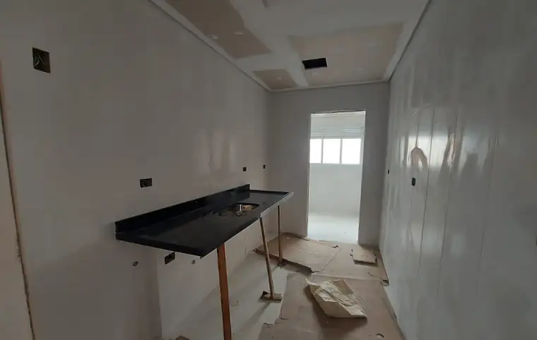 Cozinha em obra com bancada instalada, paredes revestidas e forro de gesso